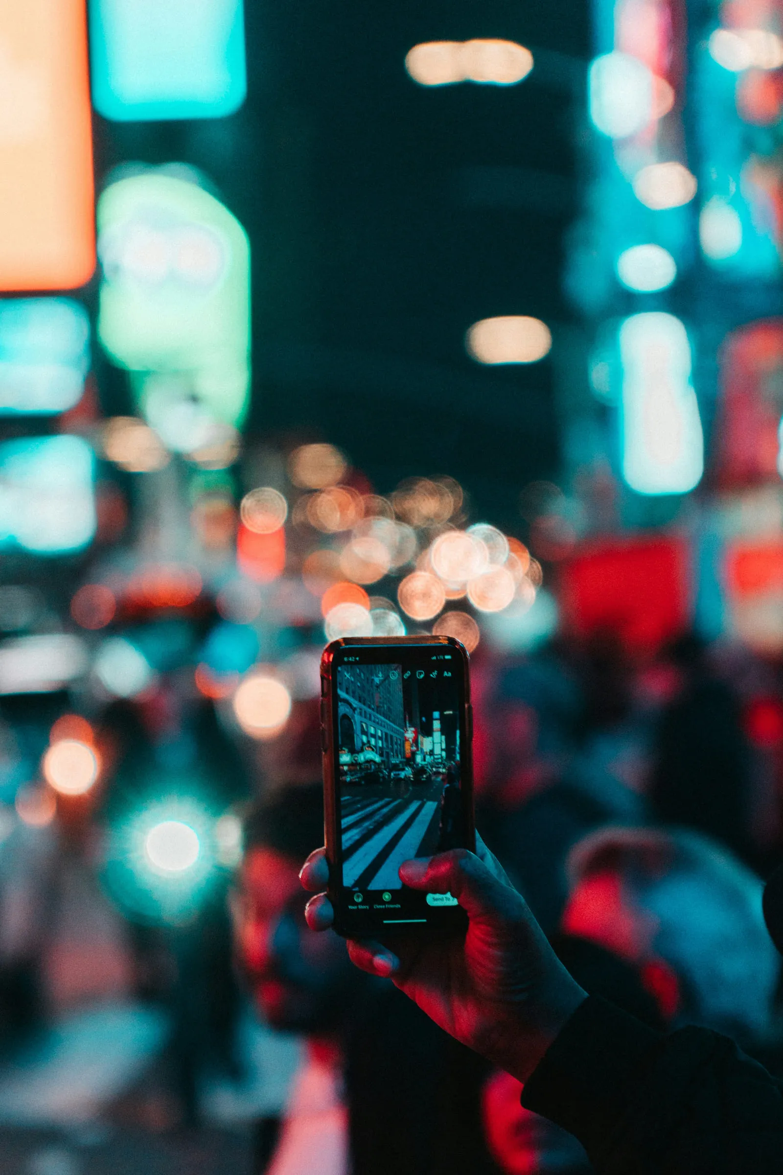 Ein Smartphone filmt eine Szene, im Hintergrund lösen sich Lichter zu warmen Kreisen auf.