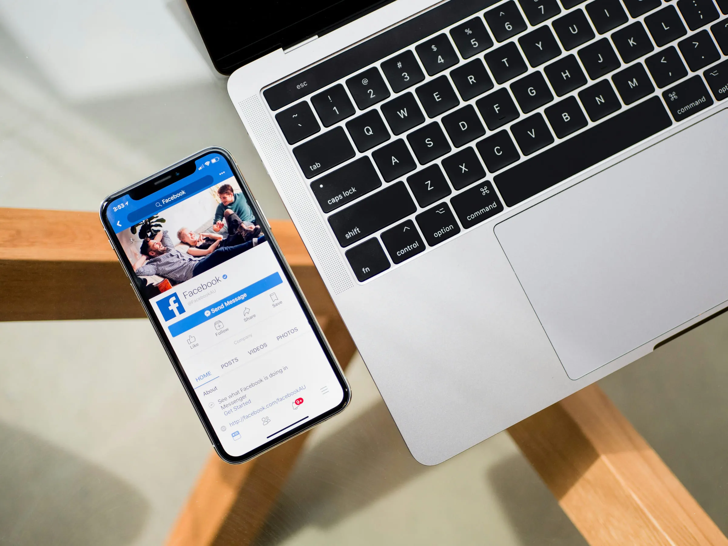 Aufgeklappter Laptop und ein Smartphone mit geöffnetem Social-Media-Profil auf einem hellen Tisch.